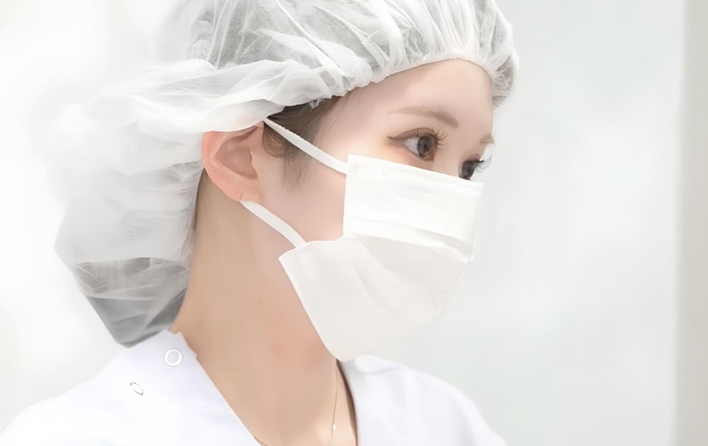 マスクとヘアキャップを着けた女性医療従事者の横顔