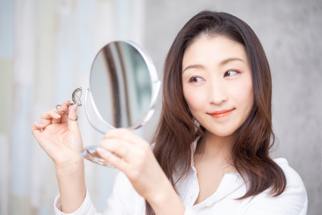 鏡で顔を見る女性