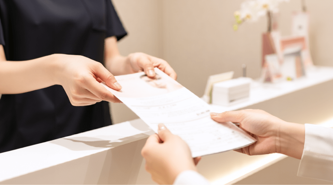 受付で書類を手渡している様子