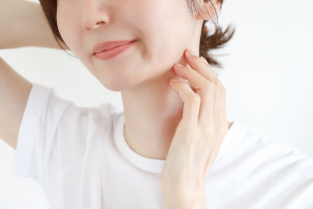 首と顎に触れる女性