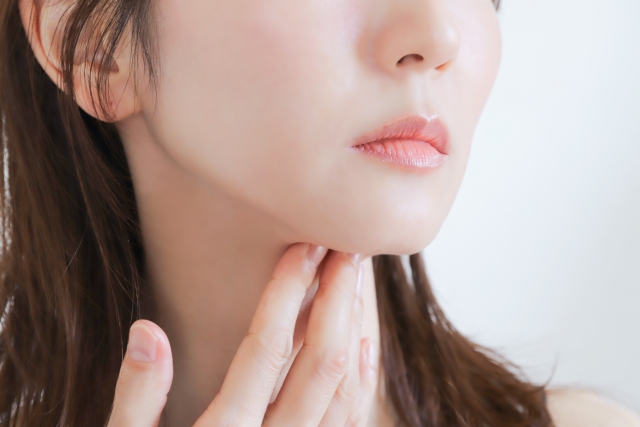 顎と首筋に触れる女性