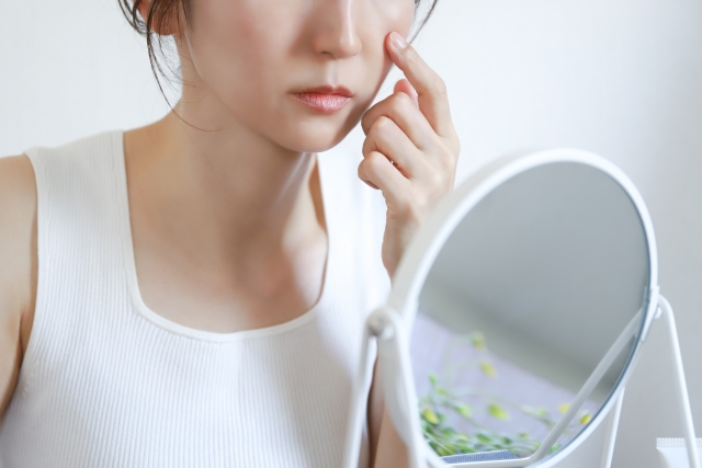 鏡でほうれい線を触る女性