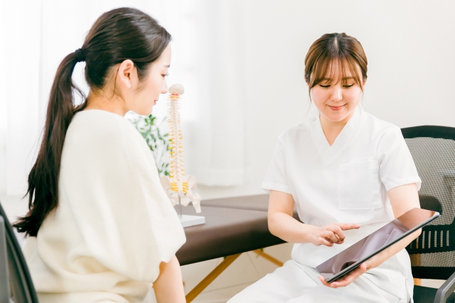 女性の施術者がタブレットを使って患者に説明