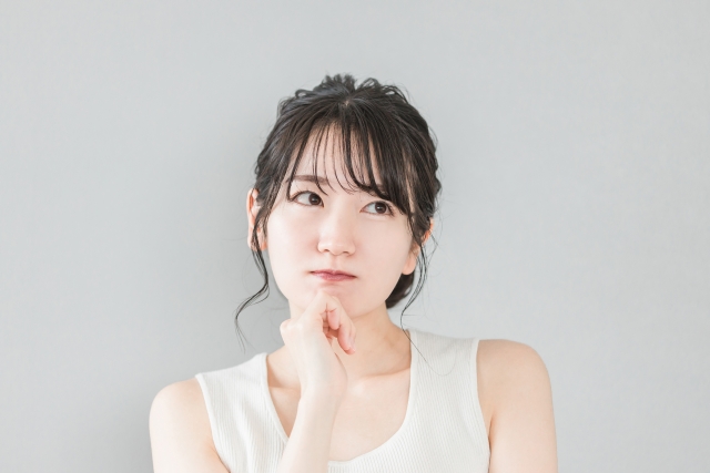 顎に手を当てて考え事をしている女性