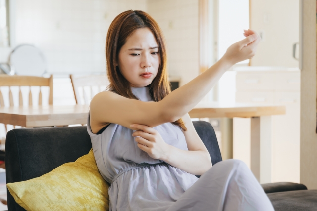 二の腕をつまみ悩む女性