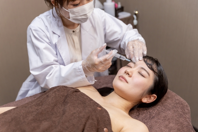 おでこに脂肪注入を行う医師と患者