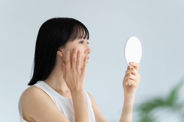 頬を鏡で見る女性